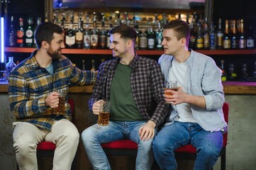 Obraz premium Soccer fans at the bar. Happy football fans cheering at bar and drinking beer while bartender serving beer at the background