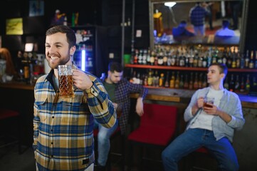 Handsome bearded man drinking beer at the bar counter in pub