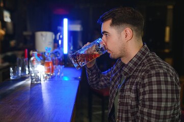 Handsome bearded man drinking beer at the bar counter in pub