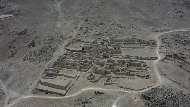 An old abandoned stone town on rocky mountain side. Drone orbits around flying high up in the sky. Located in Lurin district of Lima, Peru. Recorded in 4k quality.