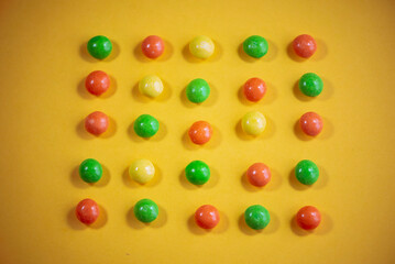 multi-colored dragee in rows on a yellow background