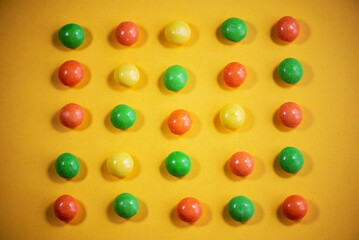 multi-colored dragee in rows on a yellow background