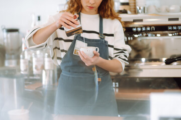 Female barista making coffee in coffee shop counter. Takeaway food.
