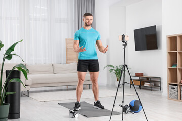 Trainer streaming online fitness lesson with phone at home