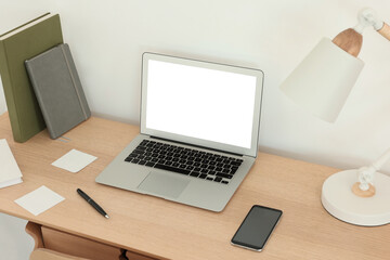 Fototapeta premium Comfortable workplace at home. Modern laptop with blank screen and lamp on wooden desk. Mockup for design