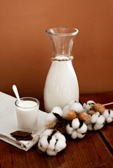 a jug of milk decorated with a sprig of cotton with a slice of chocolate