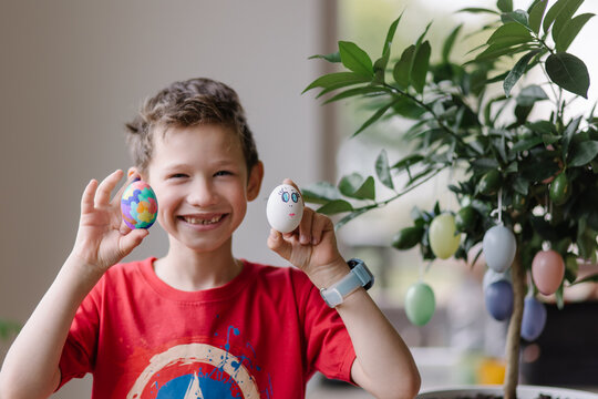 Cheerful boy holding painted eggs and smiling. Sincere children's laughter. Easter celebration. Lifestyle portrait of a schoolboy with a toothless smile. Family Traditions. Good mood for the holidays