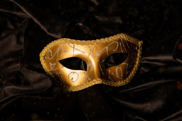 Closeup of golden carnival mask on black curtain table