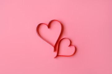 Two red hearts made of paper on a pink background. Background for a valentine's postcard. valentine day. Love concept.
