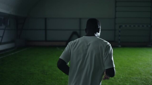 athletic young black man training in football hall, back view, medium slow motion shot