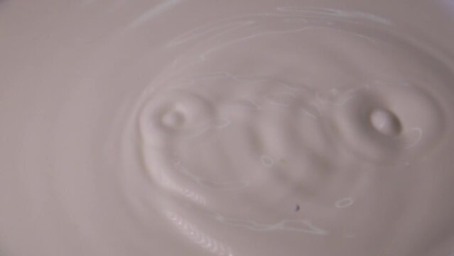 Drops of milk fall from above in super slow motion