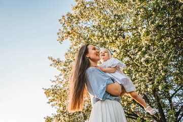 Mother and little daughter near blooming apple tree.