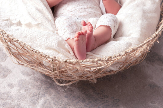 Detail of a newborn baby feet with soft white blanket. Close up picture of new born baby feet on knitted plaid
