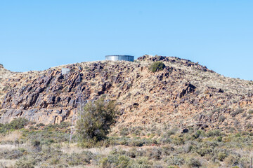 Fototapeta na wymiar Remnants of windmill, corrugated iron dam on a hill