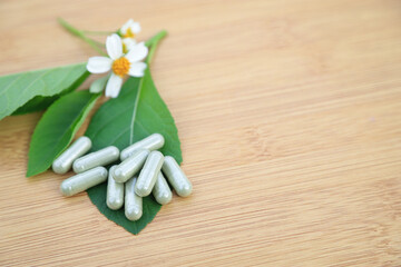 Herbal medicine in capsules from herb leaf on rustic wooden table with copy space for medical background. healthy eating with natural product for good living.