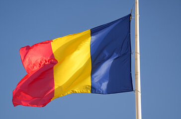 Close up view of the national flag of Romania waving against blue sky background.