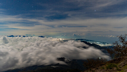 Night at the top of the Agung volcano. Panoramic view of East Java and Bali against the background of clouds. The background of the natural landscape. Bali Island, Indonesia