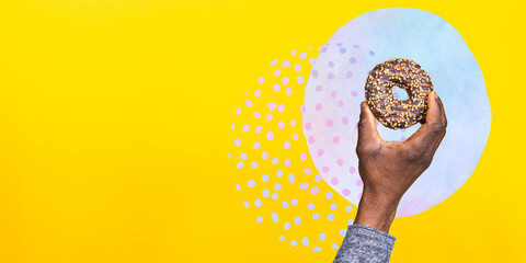 Close-up photo of african american man's hand holding donut isolated over yellow background. Junk food. Diet concept. Vector collage illustration.