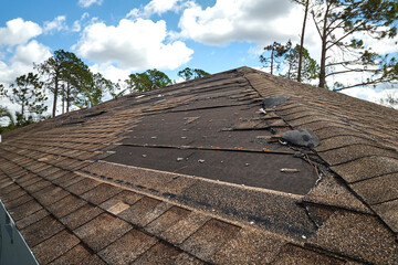 Wind damaged house roof with missing asphalt shingles after hurricane Ian in Florida. Repair of home rooftop concept - obrazy, fototapety, plakaty