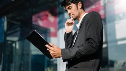 Handsome  Asian businessman using a tablet on a bench in the city