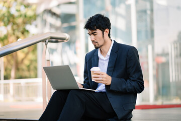 Positive Asian Entrepreneur Talking On Cellphone Using Digital Tablet During Coffee Break In City Urban Area.