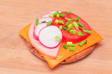 Crispy Cracker Sandwich with Tomato, Sausage, Cheese, Green Onions and Radish on Cutting Board....