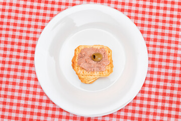 Crispy Salted Cracker with Liver Pate and Olives on White Plate. Easy Snack