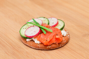 Crispy Cracker Sandwich with Salmon, Cucumber, Radish, Cottage Cheese and Green Onions on Bamboo Cutting Board. Easy Breakfast. Quick and Healthy Sandwiches. Crispbread with Tasty Filling