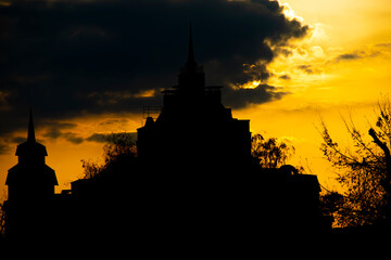 the silhouette of the building against the background of the setting sun behind a cloud