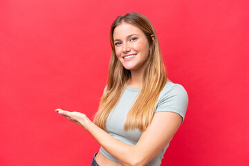 Young beautiful woman isolated on red background presenting an idea while looking smiling towards