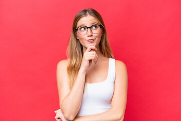 Young beautiful woman isolated on red background thinking an idea while looking up