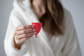 Young woman holds a menstrual cup in her hands. Feminine hygiene alternative product instead of...