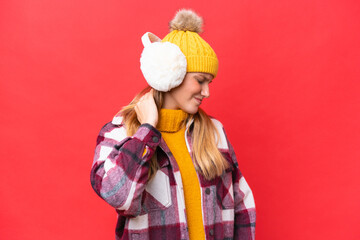 Young beautiful woman wearing winter muffs isolated on red background with neckache