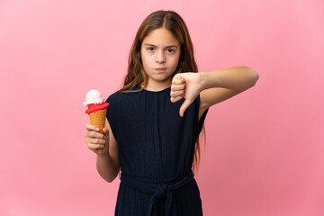 Child with a cornet ice cream over isolated pink background showing thumb down with negative...