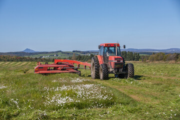 Mowing hay mower , rotary hay mower in a field on a sunny summer afternoon.  Agricultural machinery equipment.  