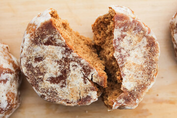 Glazed gingerbread broken in half on a wooden table.