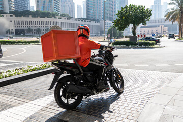 A food delivery courier is driving an order to a customer's home on a moped. takeaway food during...
