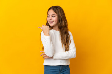 Child over isolated yellow background pointing to the side to present a product