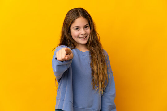 Child over isolated yellow background pointing front with happy expression