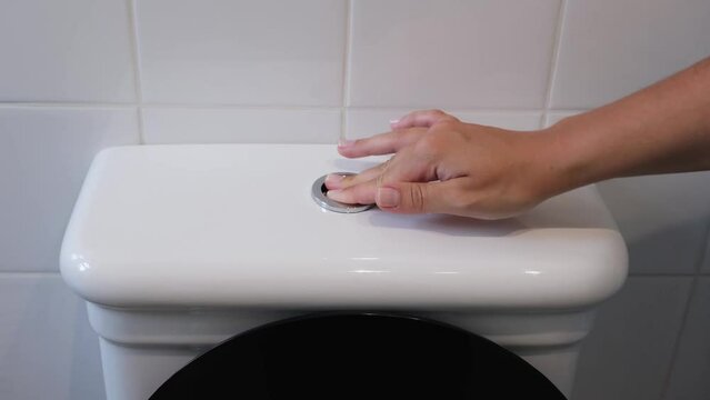 Finger of a woman hand presses the toilet flush button, close up video