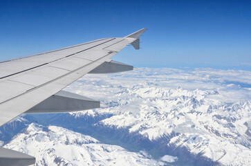 Fototapeta na wymiar Wing of a plane flying over snowy mountains