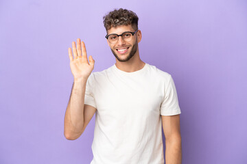 Delivery caucasian man isolated on purple background saluting with hand with happy expression