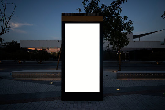 Electronic modern empty scoreboard on the background of a city street in the evening. Blank mock up of vertical street poster billboard on city background