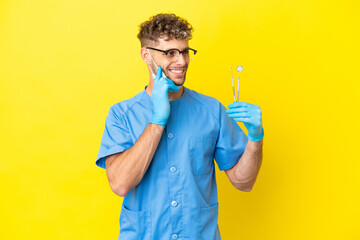 Dentist blonde man holding tools isolated on background thinking an idea while looking up