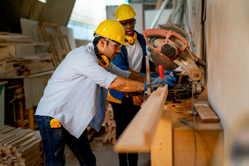 Caucasian carpenter man shows example to his African American co-worker for using electrical saw to...