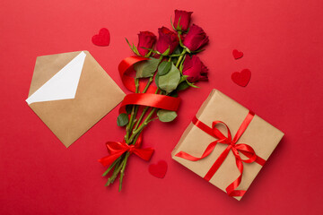 Valentines day gift box with red roses on color background, top view