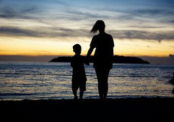 Mother and son walking on the shore of Kinabalu beach during sunset hour