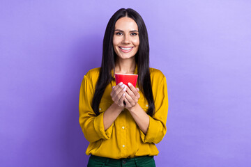 Portrait of charming cheerful lady beaming smile arms hold coffee cup isolated on purple color background
