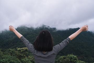 A young women is speading out her arms to get fresh and relax after seen the stunning mountain view  on the top of the viewpoint in the morning