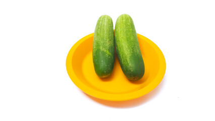 Two cucumbers on a yellow plate isolated white background